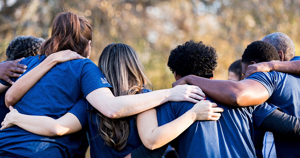 A group of students standing in a row with their arms around each other, from behind