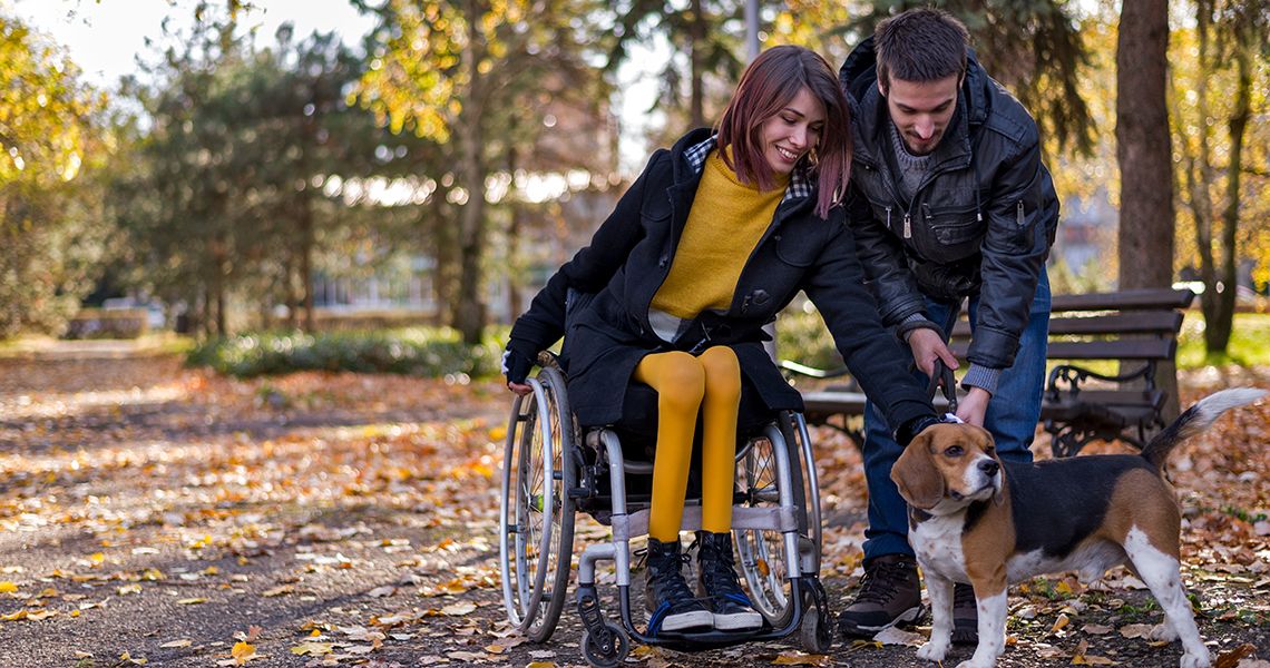 Disabled girl with boyfriend playing with dog in the park