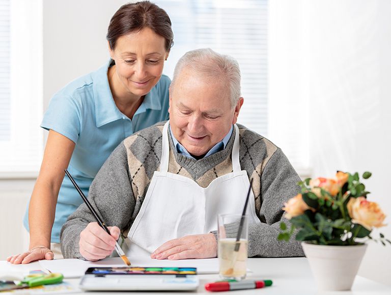 woman helping an elderly man paint