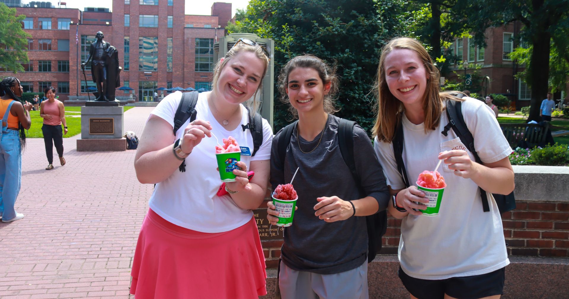students smiling in university yard with kona ice