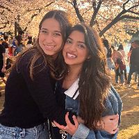 Iman Nasir hugging fellow student in front of cherry blossoms