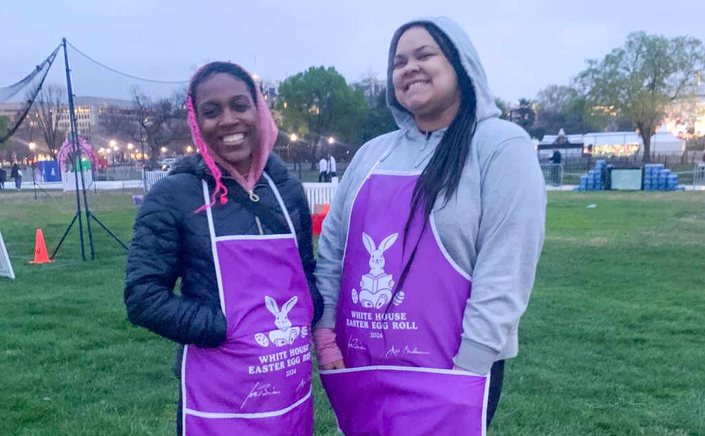 OT Student Quenita and Alicia smiling in Easter Egg Roll volunteer aprons