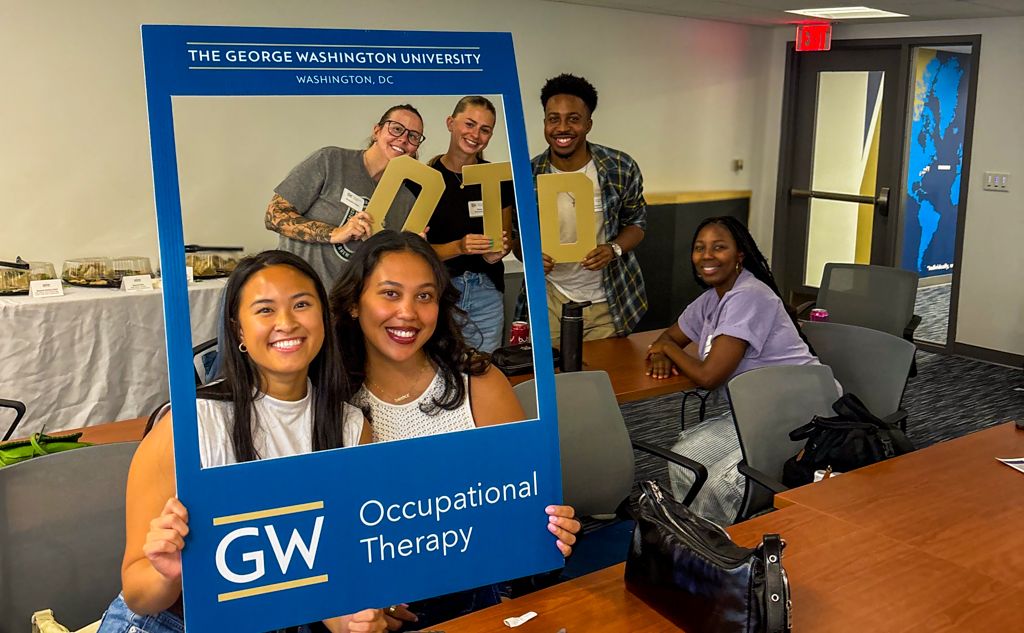7 GW OT Students in Blue Picture Frame Prop holding OTD gold letters_437x287