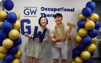 Two students holding GW OT Signs